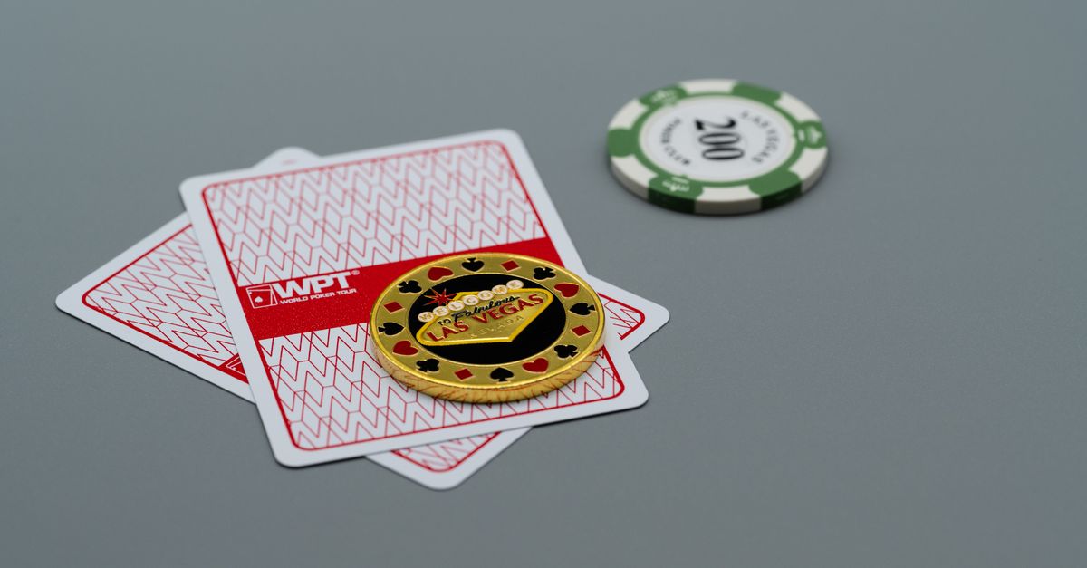 Two playing cards and poker chips, including a Las Vegas chip, on a grey background. Ideal for casino or gambling themes.